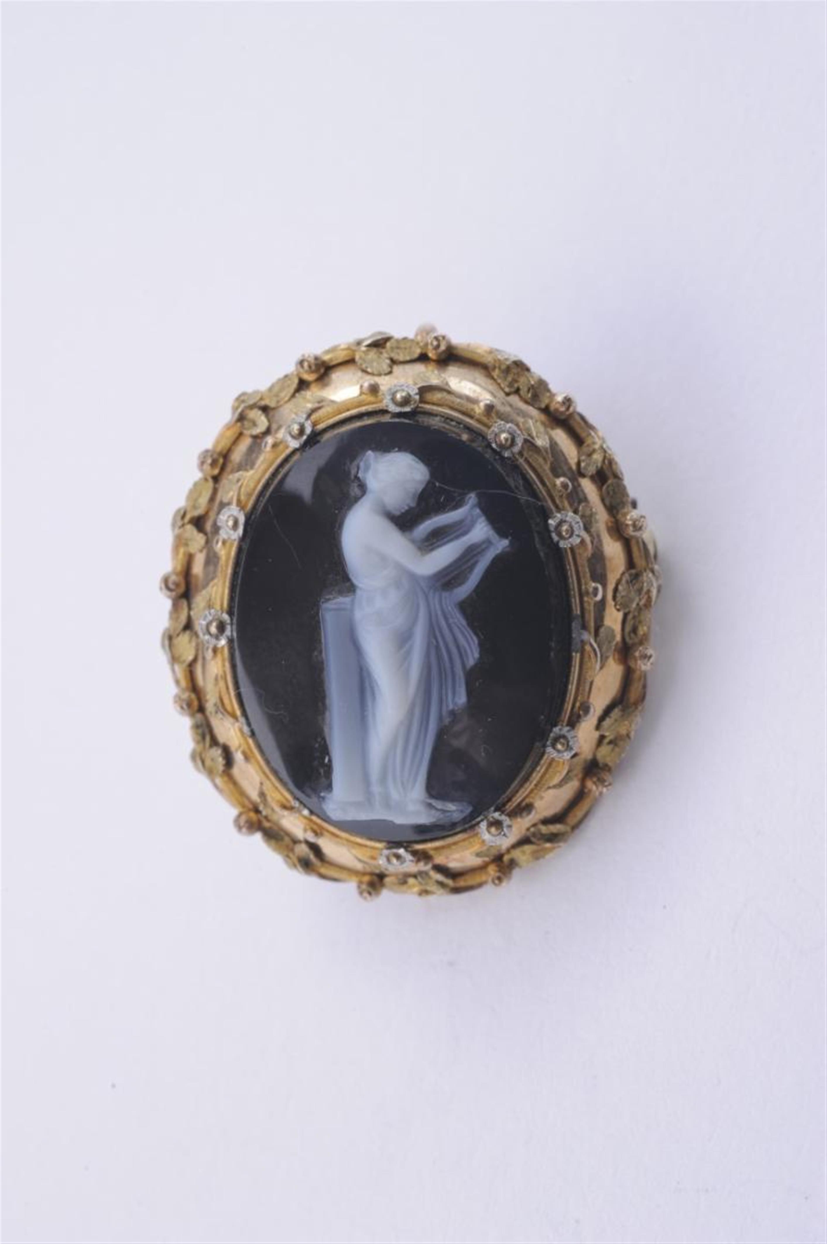 An 18k gold pendant brooch with a layered onyx cameo depicting a standing Muse. - image-1