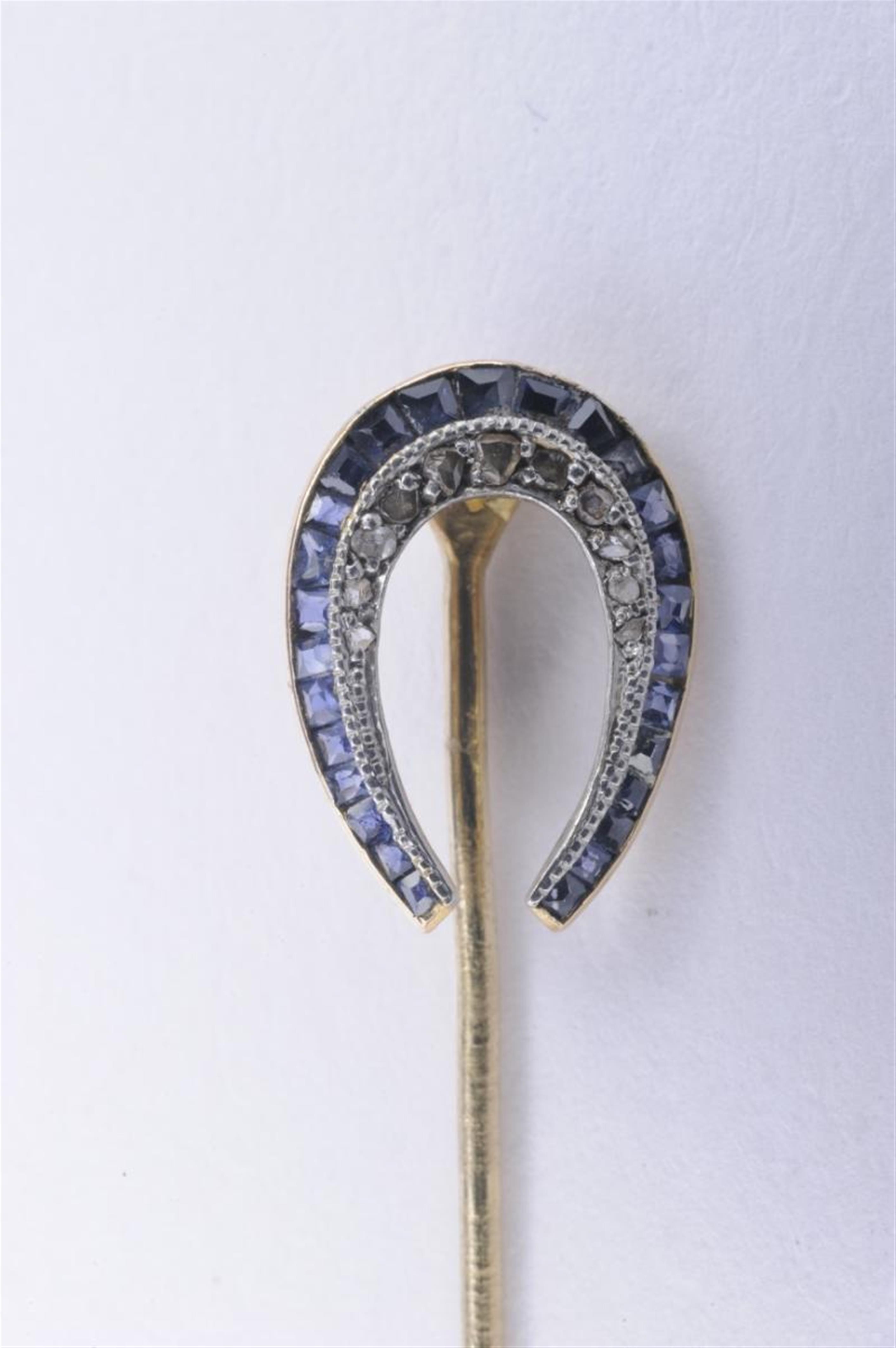 An 18k gold tie-pin formed as a horseshoe set with rose diamonds and calibré-cut sapphires. - image-1