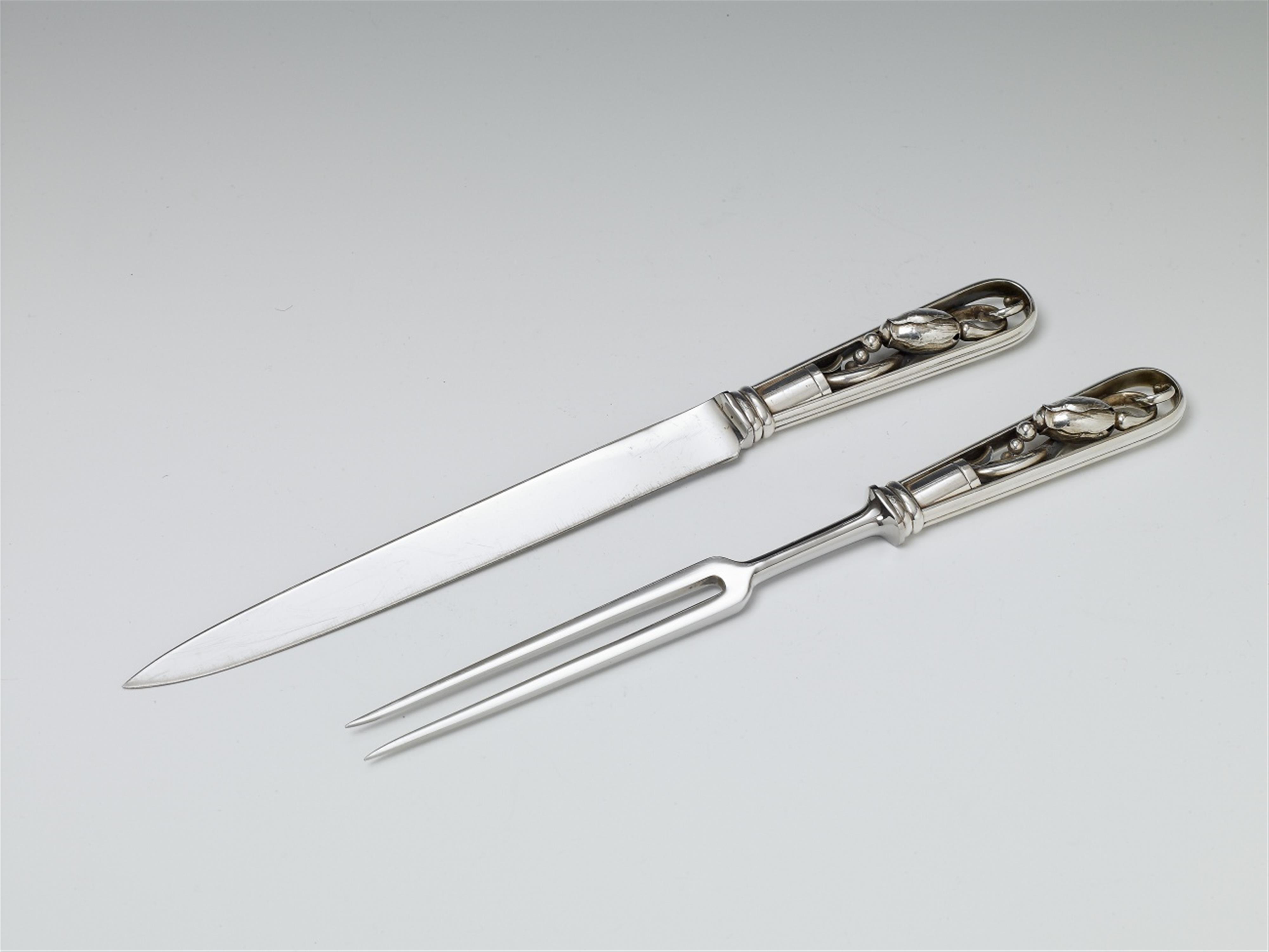 A Copenhagen silver set of carving cutlery. Blossom pattern. The blades/fork of steel. Marks of Georg Jensen, designed 1919; made 1945 - 76. Tranchierbesteck No. 84 - image-1