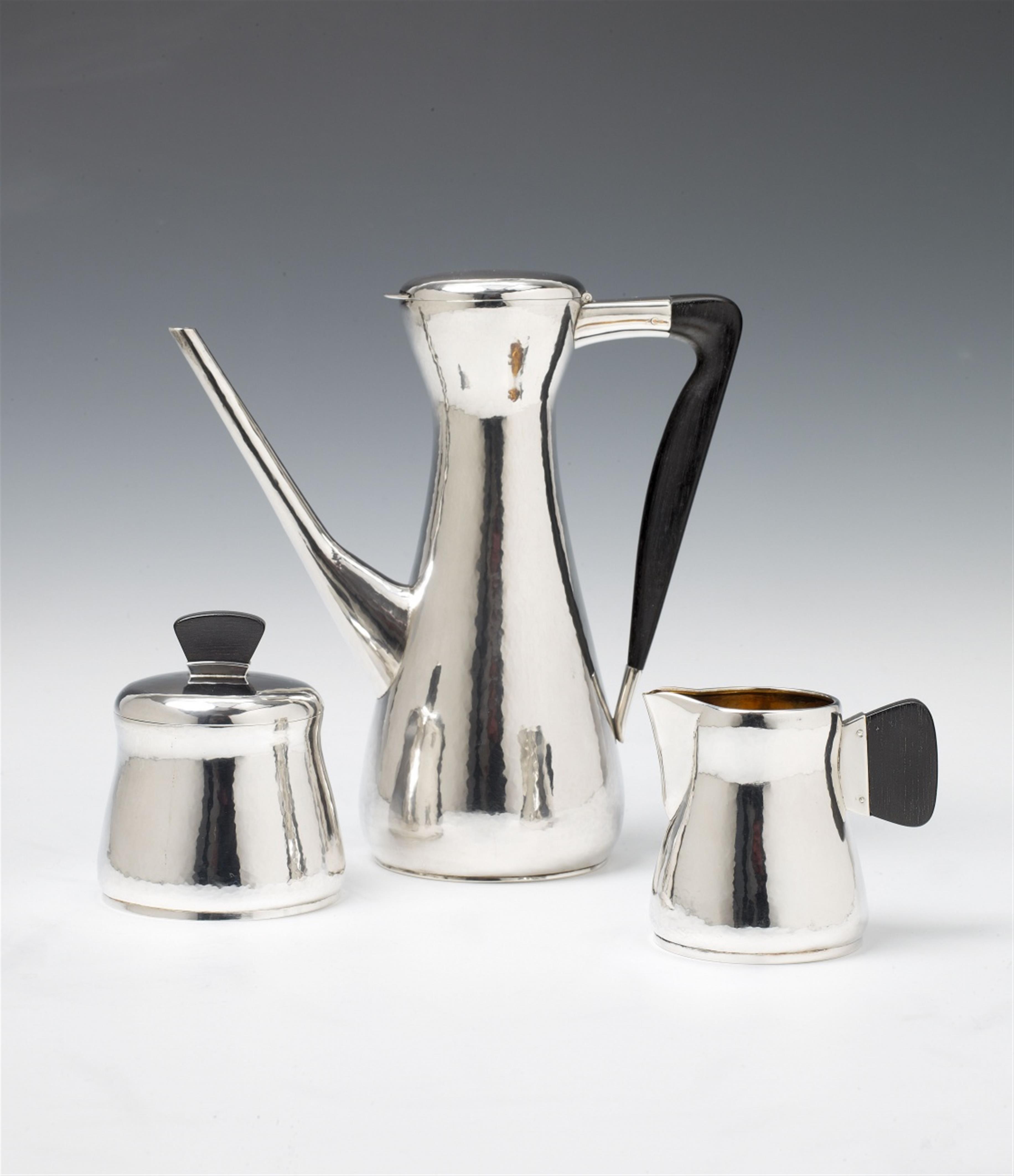 A Cologne silver interior gilt mocca service. Comprising coffee pot, milk jug and sugar box. The handles and finial of ebony. Marks of Wilhelm Nagel, 1950s. - image-1