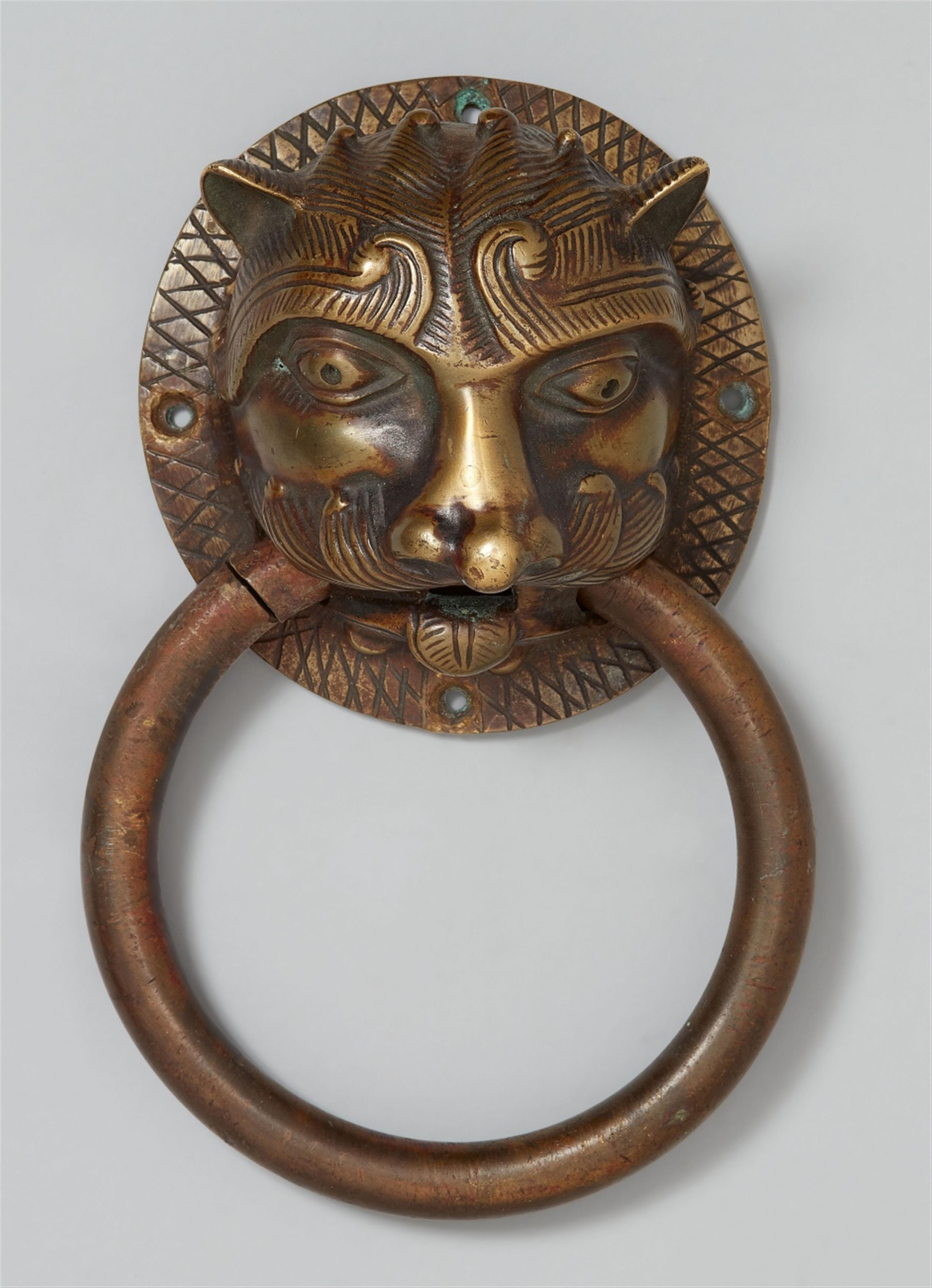 A Romanesque style bronze door knocker formed as a lion's head mask - image-1