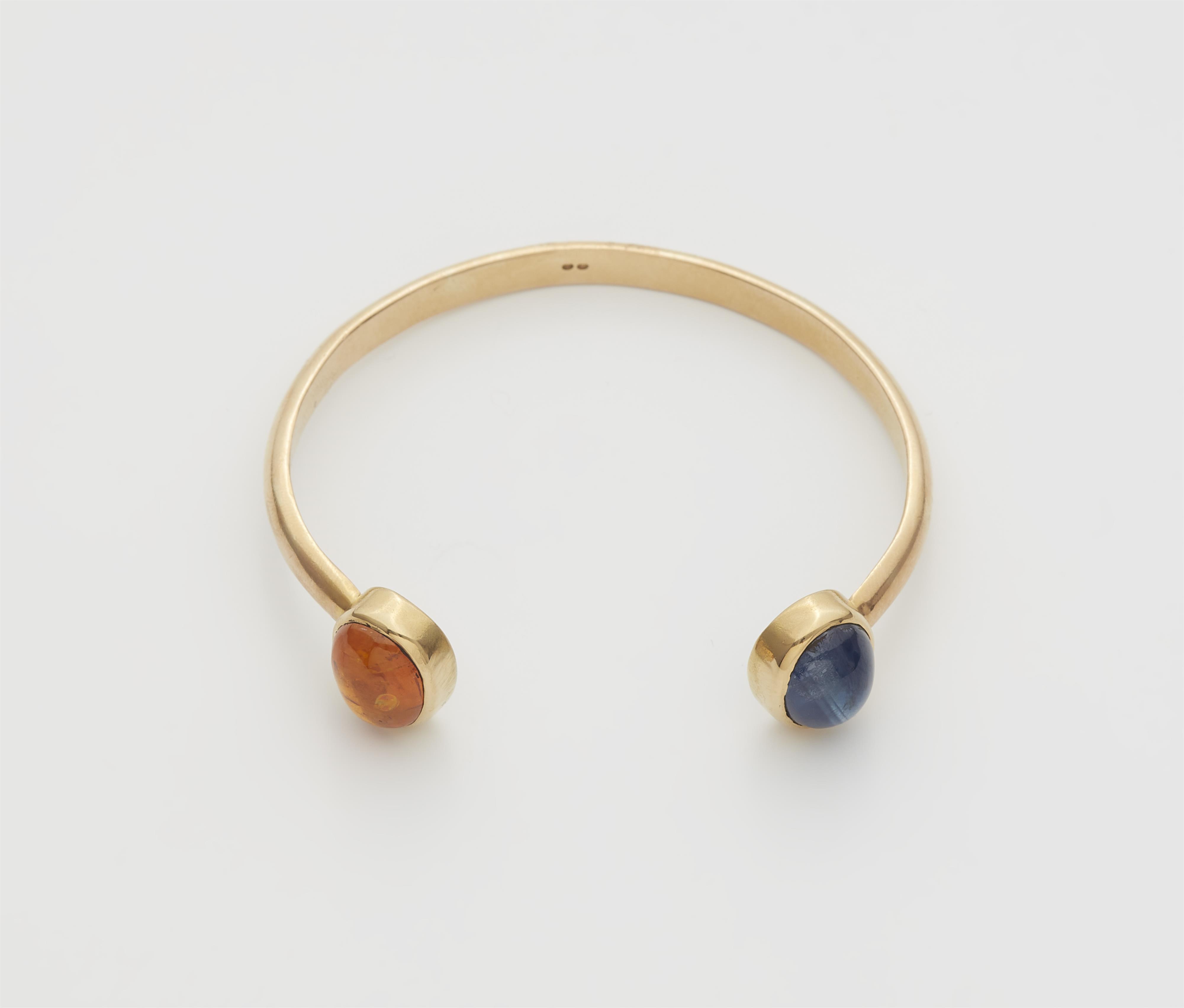 An Austrian 18k gold bangle with two large sapphire cabochons. - image-1