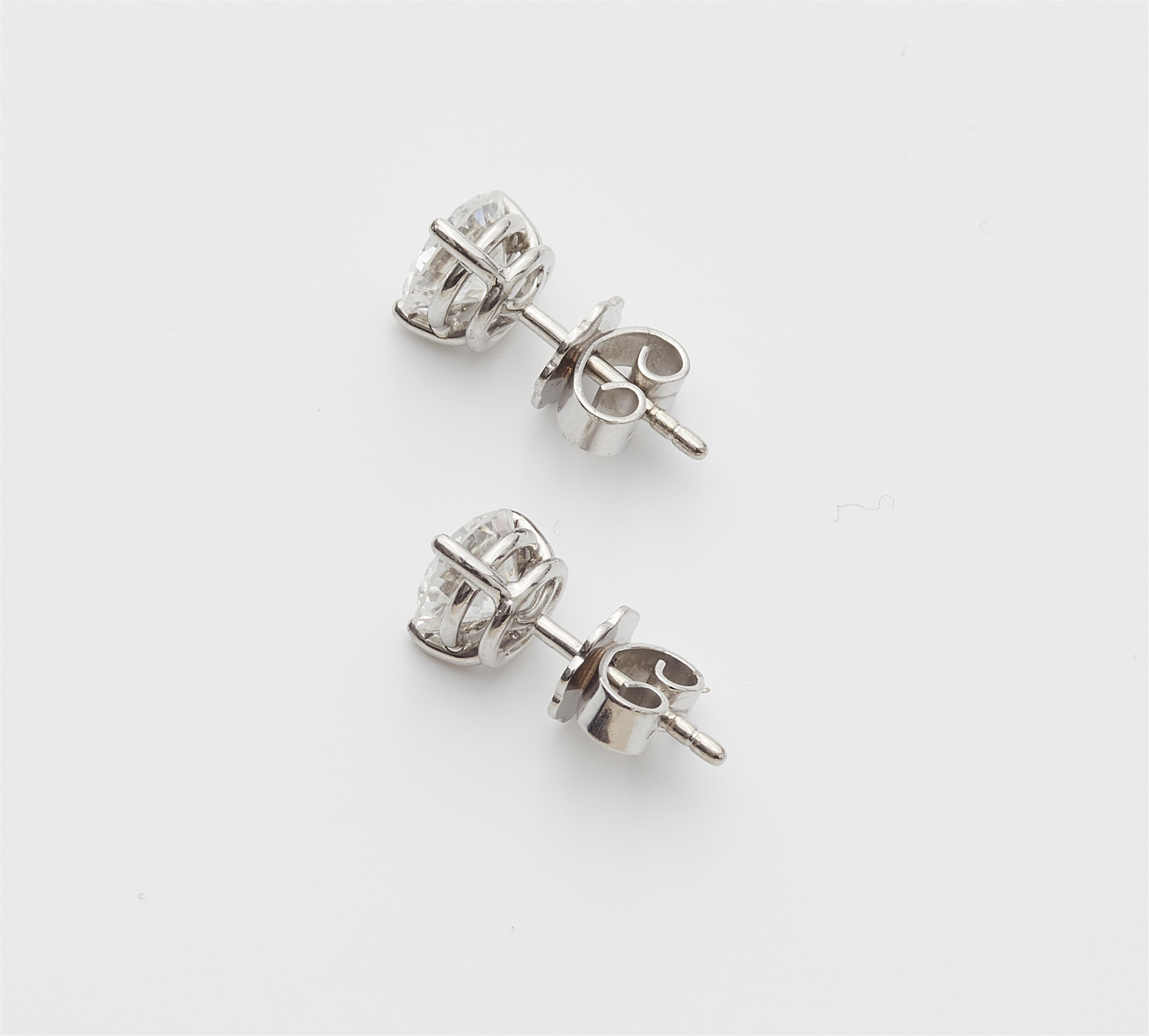 A pair of 18k white gold and diamond solitaire stud earrings. - image-2