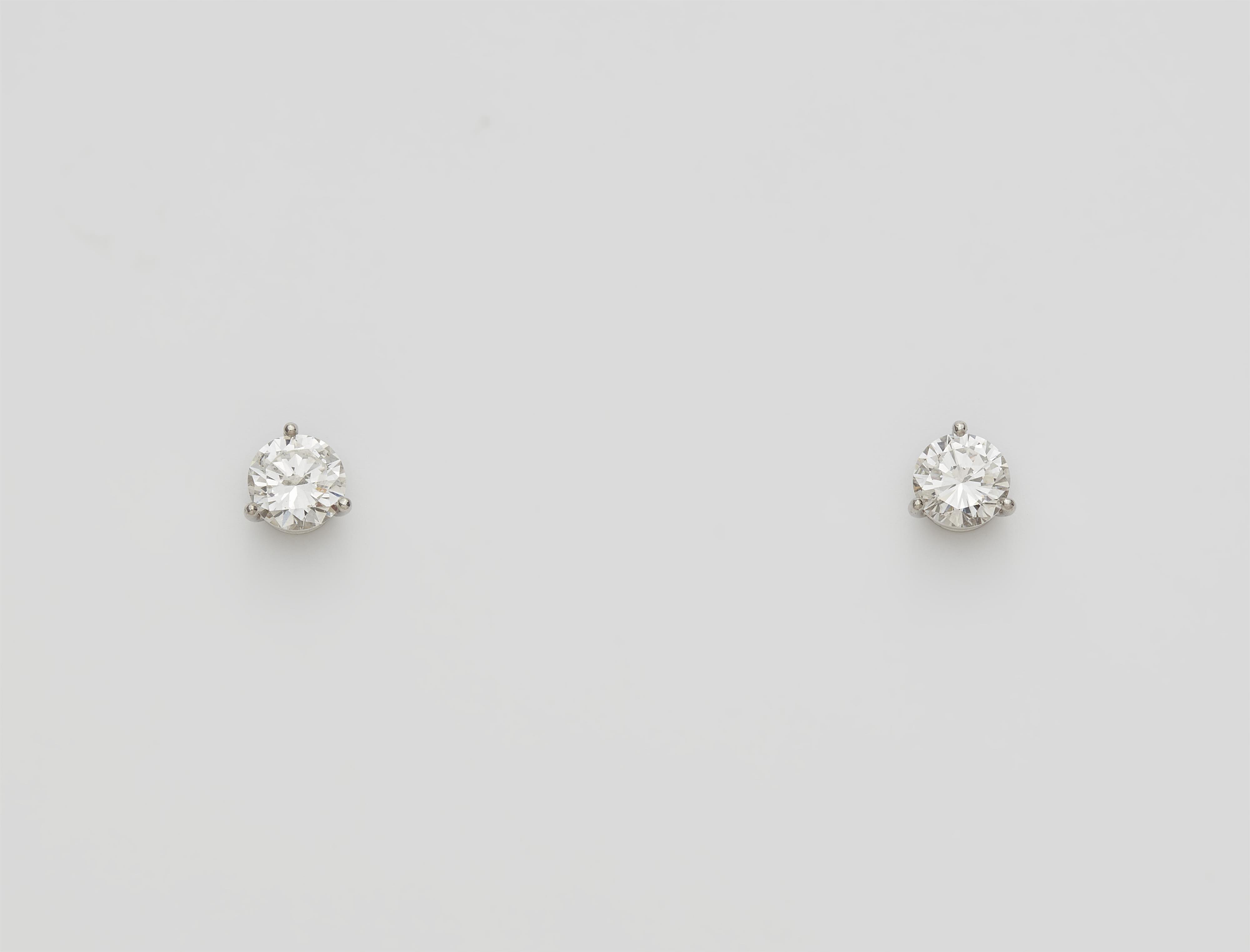 A pair of 18k white gold and diamond solitaire stud earrings. - image-1