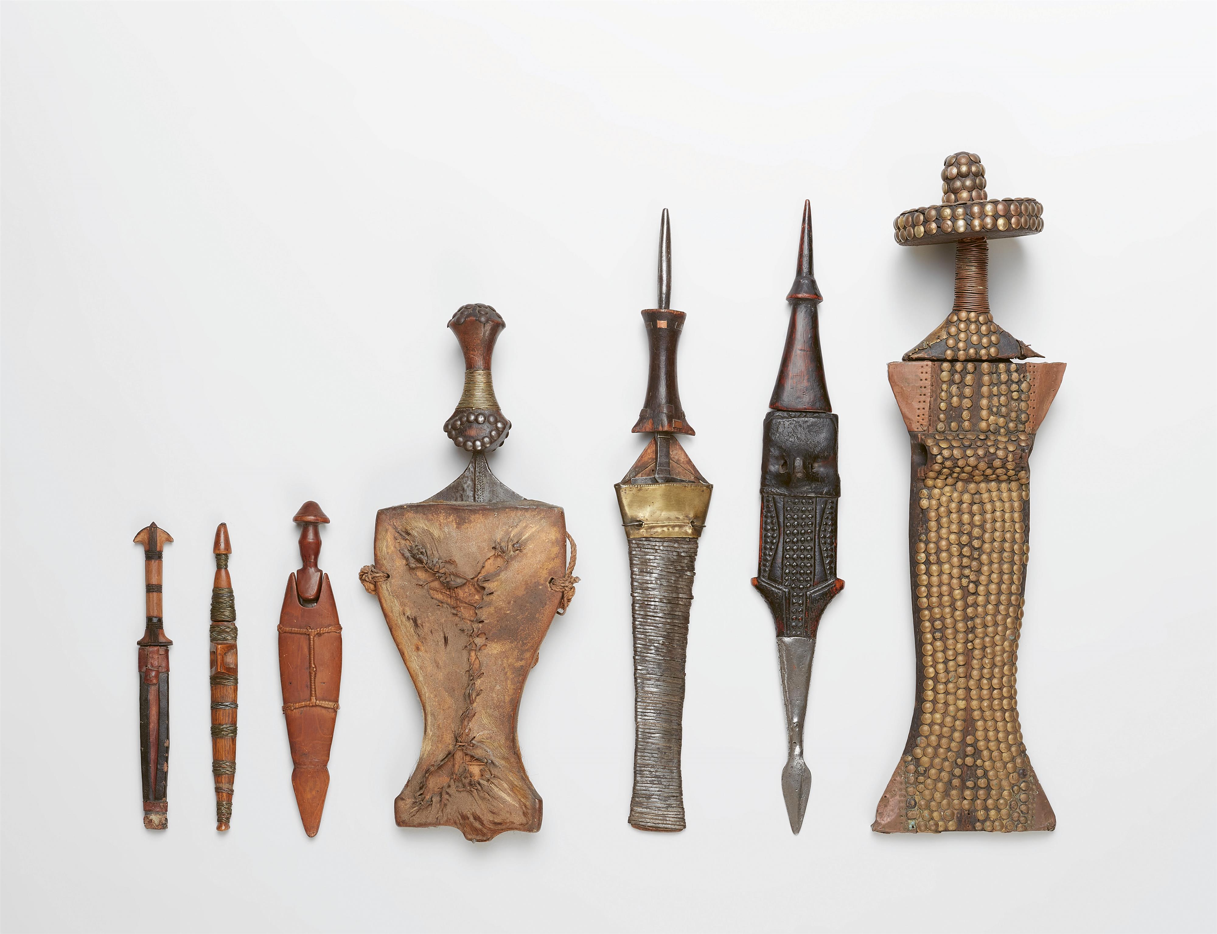 SEVEN AFRICAN KNIVES IN SHEATHS - image-1