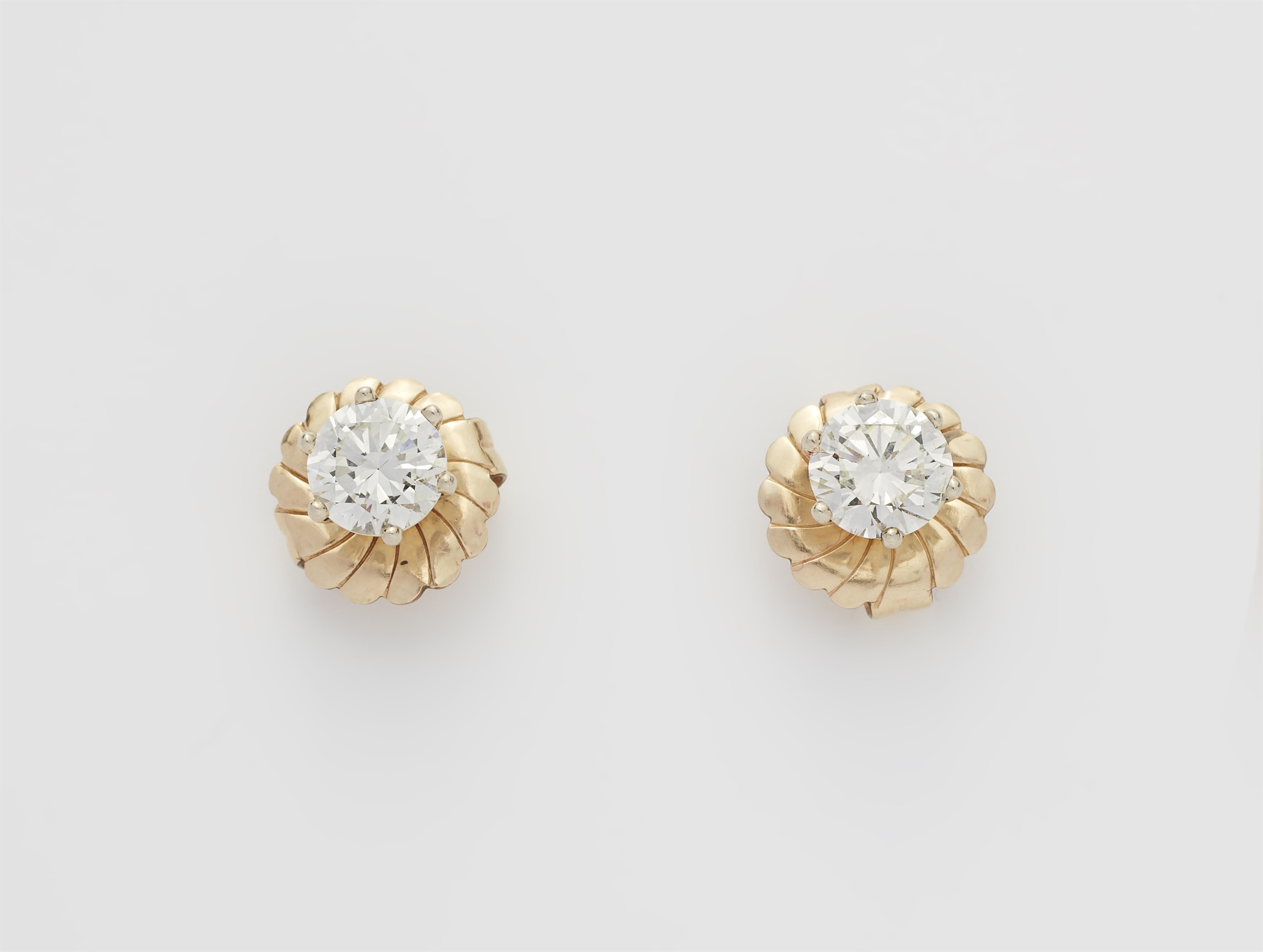 A pair of 14k gold and diamond solitaire stud earrings. - image-1