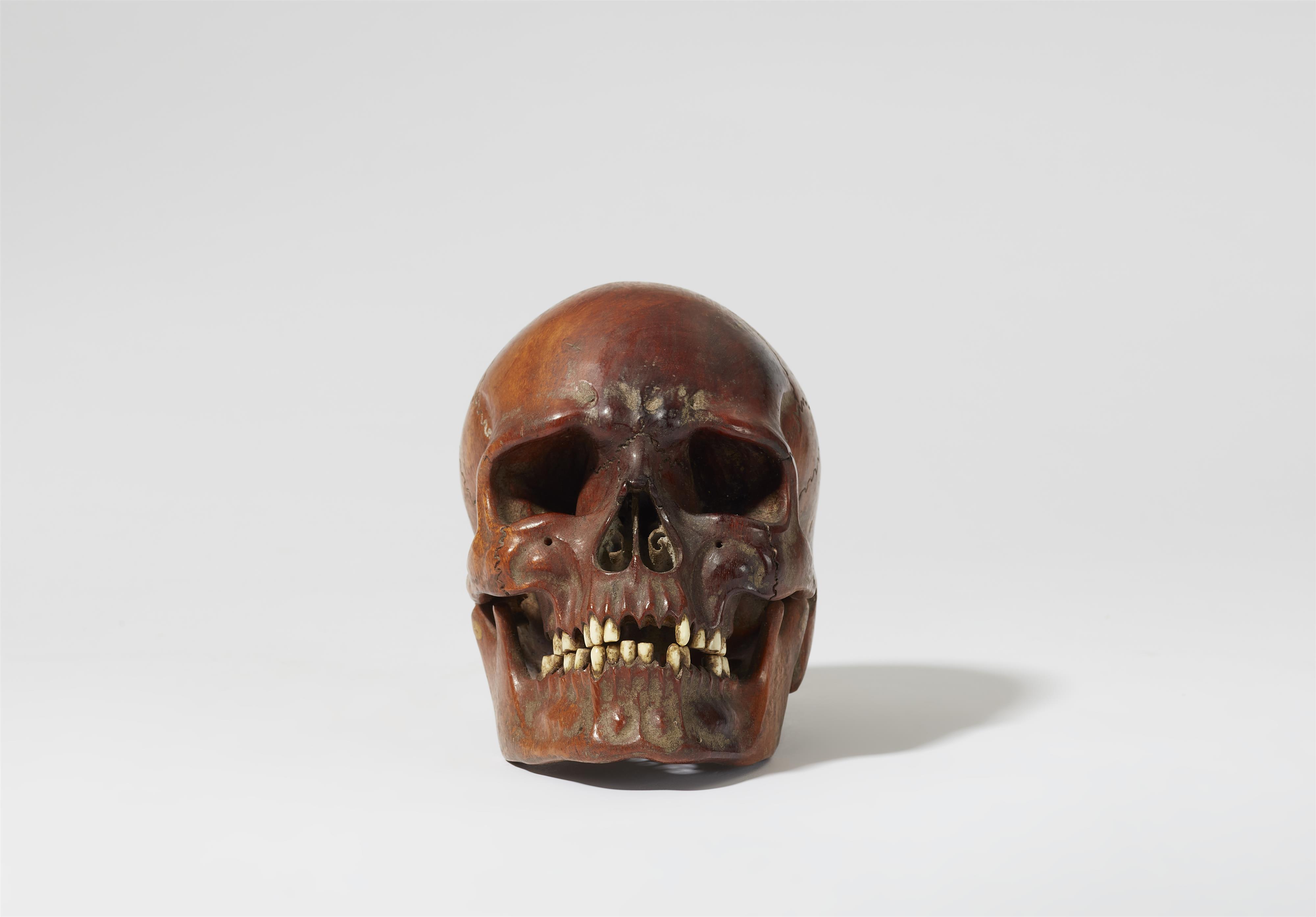 A carved walnut and bone skull - image-1