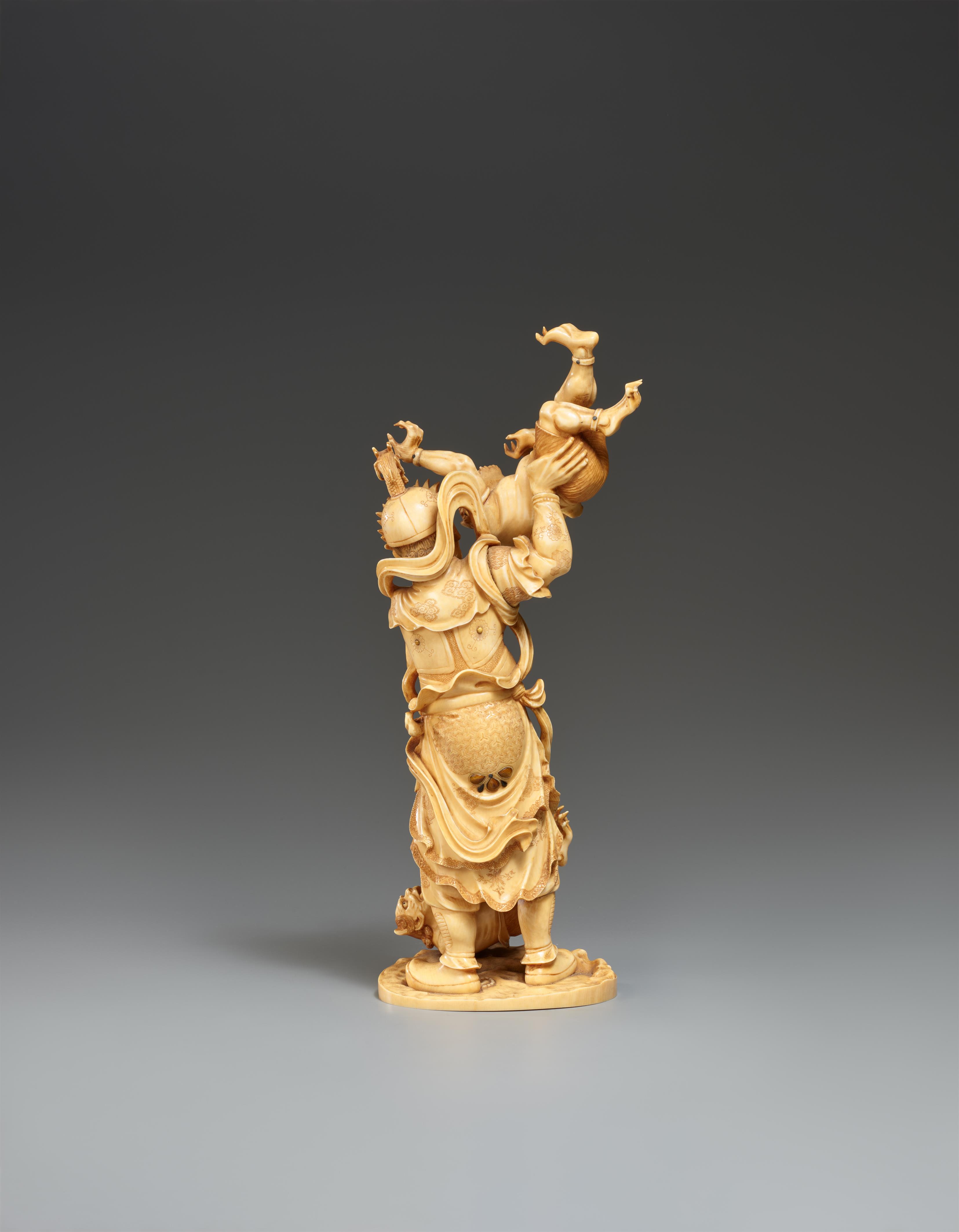 A sectional, lightly stained ivory okimono of a guardian figure with two oni. Late 19th century - image-2