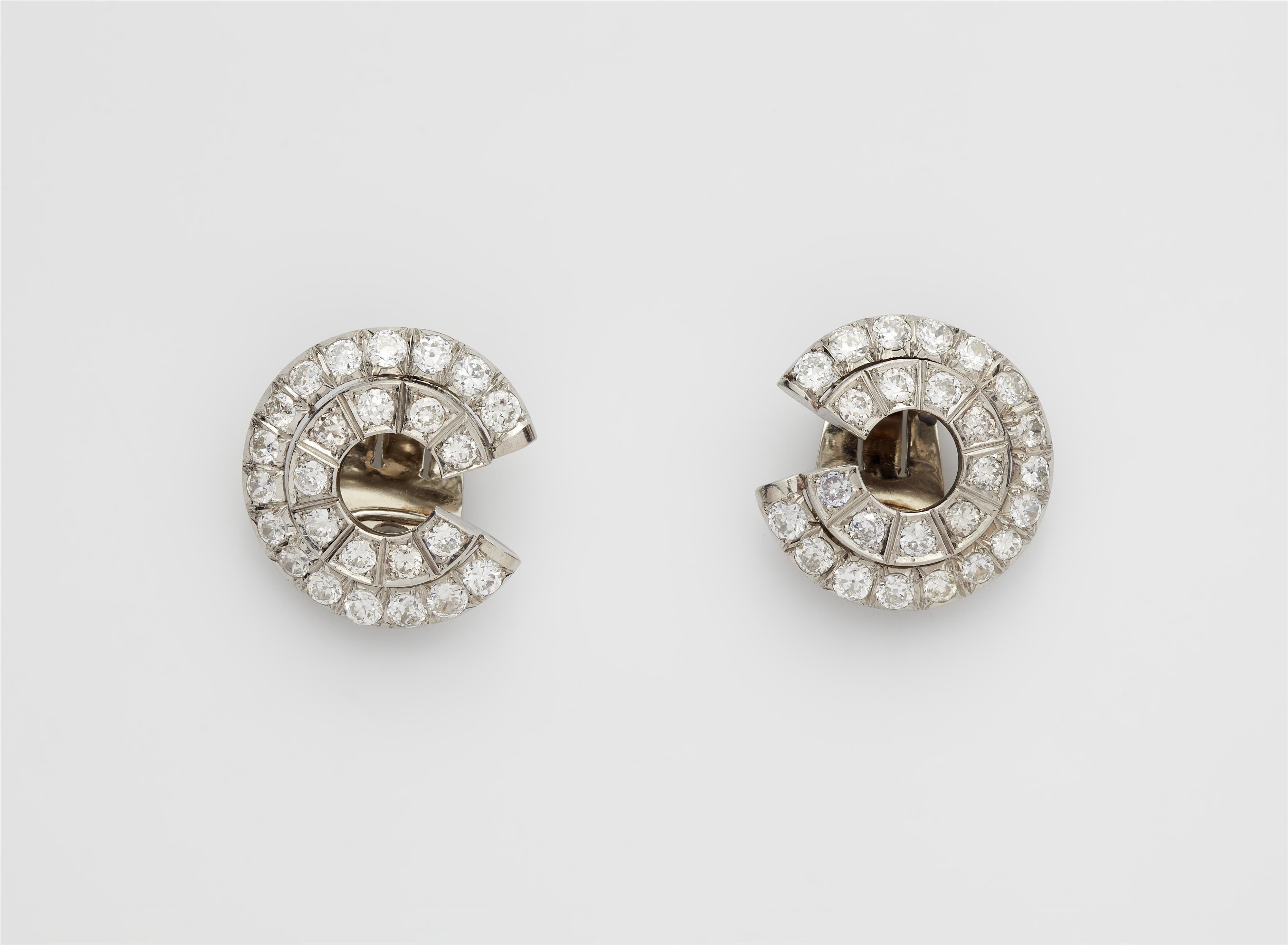 A pair of platinum and diamond swirl clip earrings with diamonds. - image-1