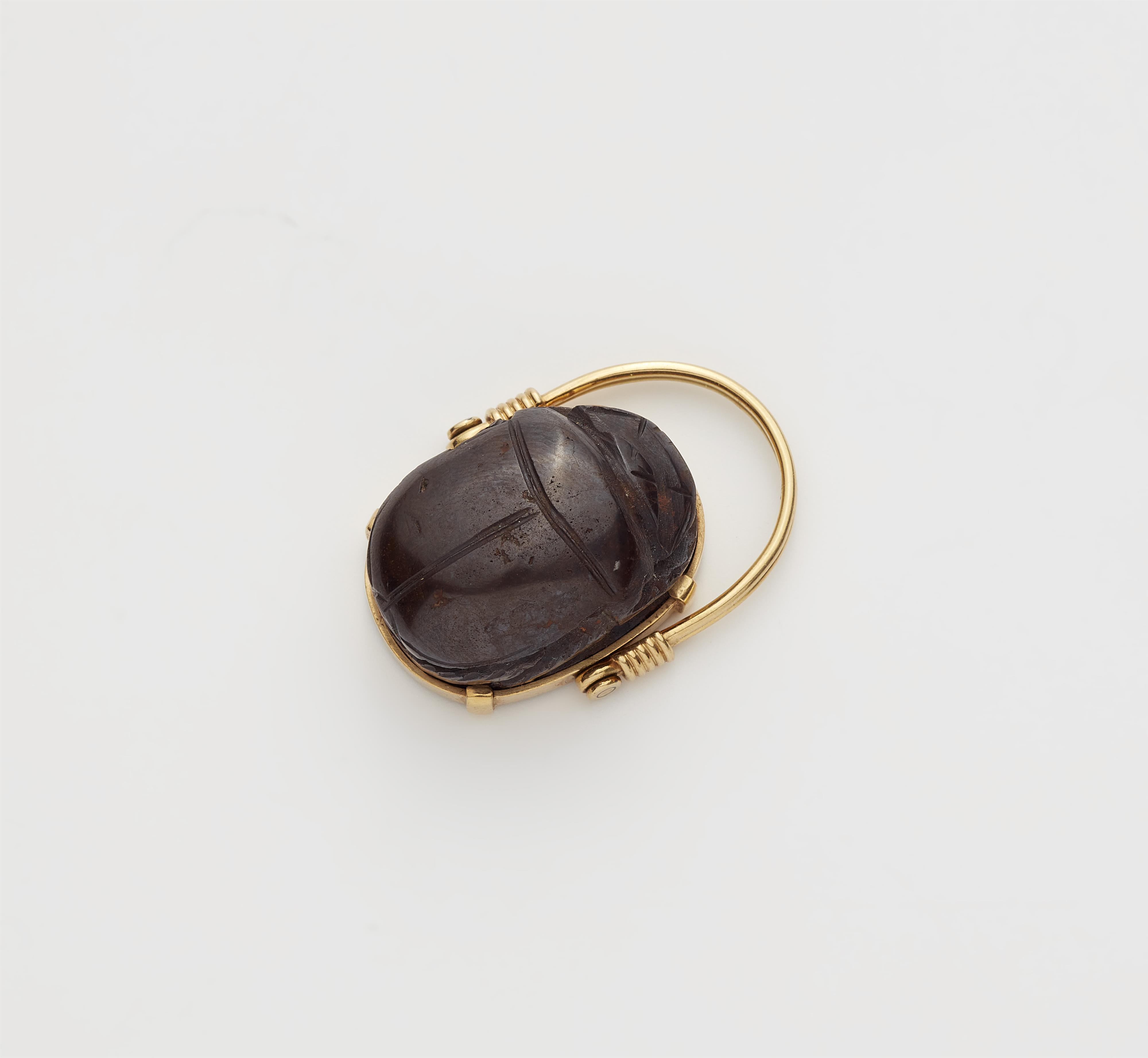 An Archäological Revival 18k gold and carved brown hardstone scarab swivel ring. - image-1