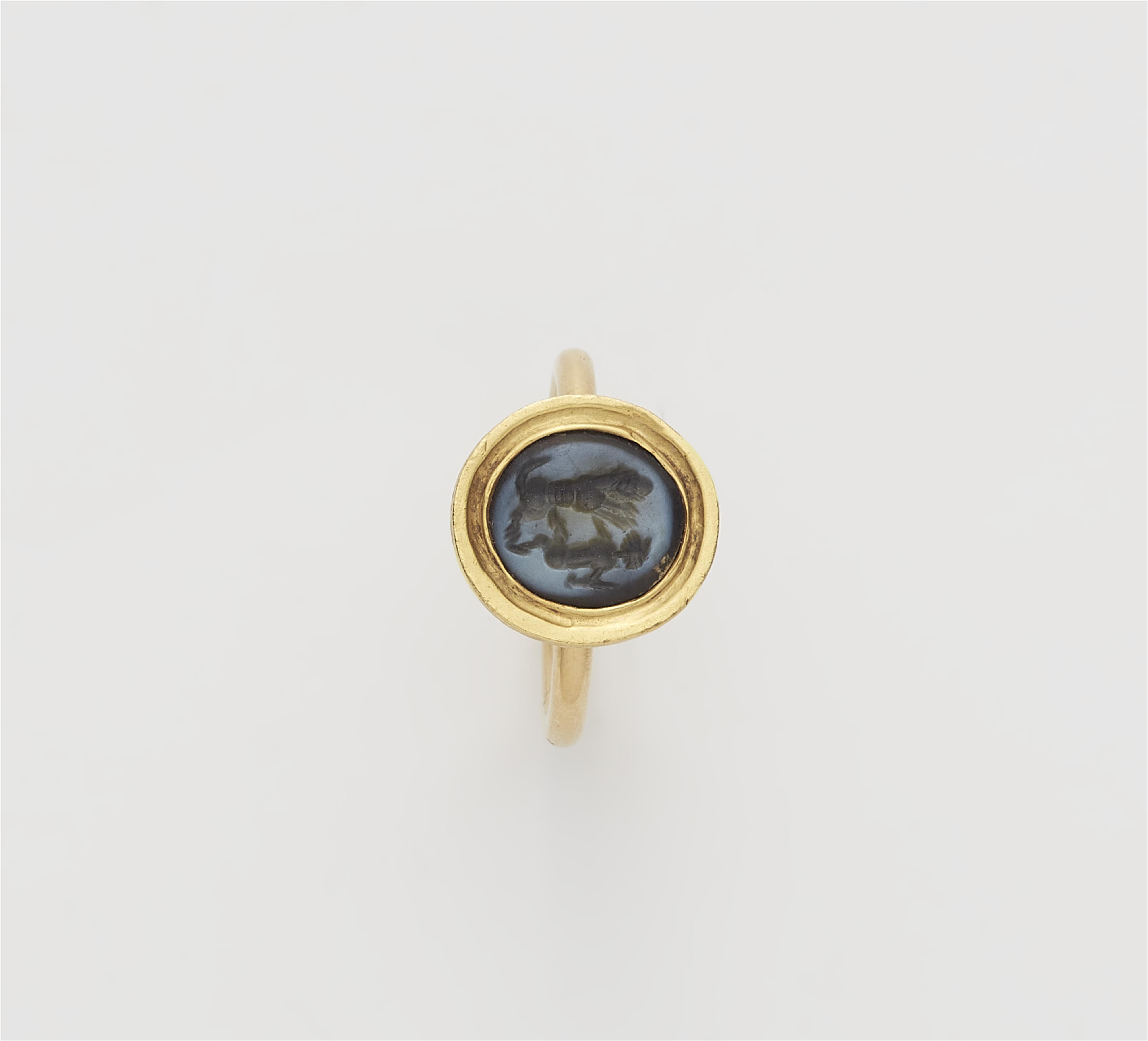 An 18k gold ring with an ancient Sassanian nicolo intaglio depicting a lion fighting with a hoofed animal. - image-1